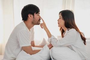 contento joven asiático Pareja abrazando, broma, jugando alegremente en cama a hogar, romántico hora a mejorar familia vinculación familia concepto. foto