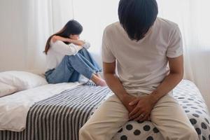 The husband is unhappy and disappointed in the erectile dysfunction during sex while his wife sleeping on the bed. Sexual Problems in Men, The concept of erectile dysfunction according. photo