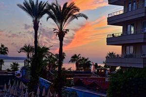 landscape of the setting sun with palm trees and buildings in Alanya Turkey on a holiday day photo