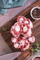 Pieces of raw oxtail and spices for cooking on a wooden board on the table top and vertical view photo