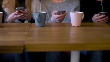 Gruppe von Menschen verwenden Handy, Mobiltelefon Telefone im ein Cafe stattdessen von kommunizieren mit jeder andere video