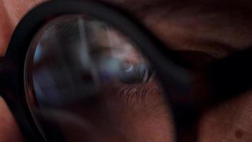 Man in glasses looking on the monitor and surfing Internet. The monitor screen is reflected in the glasses video