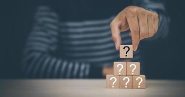 Hand hold Wooden cube block in question mark mean what on cement table background, column of wooden blocks with question sign mark. copy space,FAQ frequently asked questions, Answer, Information photo