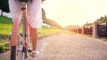 joven hermosa mujer montando un bicicleta a puesta de sol. lento movimiento video