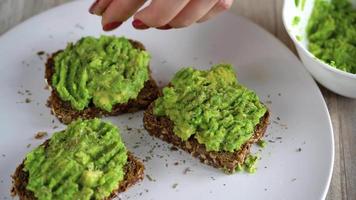 diffusione schiacciato avocado su crostini e spruzzatina con sale e spezie. salutare vegano prima colazione. video