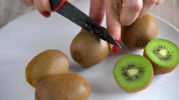 weiblich Hände Schnitt das Kiwi mit ein Messer, schließen oben video