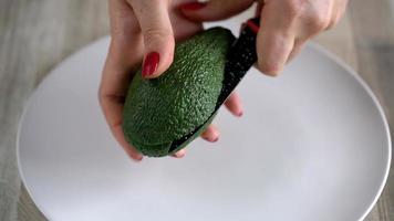 Woman opens avocado. The concept of modern healthy eating video