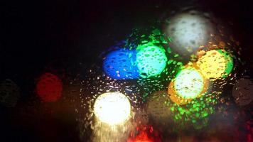 Close up rain drops on car window glass with blurred night city car lights bokeh as background video