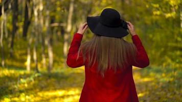 Porträt von ein schön nachdenklich Mädchen im ein rot Mantel mit ein Gelb Ahorn Blatt im das Hintergrund im das Herbst Wald. schleppend Bewegung video