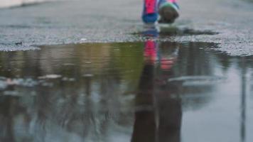 Close up shot of legs of a runner in sneakers. Female sports man jogging outdoors in a park, stepping into muddy puddle video