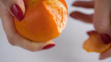 Women's hands peel the peel of tangerine, mandarin slices are piled on a plate video