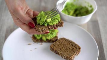 diffusion en purée Avocat sur pain grillé et saupoudrer avec sel et épices. en bonne santé végétalien petit déjeuner. video