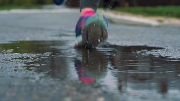 stänga upp skott av ben av en löpare i sneakers. kvinna sporter man joggning utomhus i en parkera, stepping in i grumlig pöl video