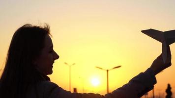 mulher lançamentos papel avião contra pôr do sol fundo. conceito do querendo para ir em período de férias ou viagem video