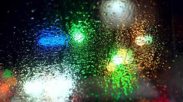 Close up rain drops on car window glass with blurred night city car lights bokeh as background video