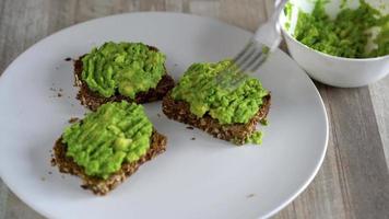 verspreiden gepureerd avocado Aan geroosterd brood en bestrooi met zout en specerijen. gezond veganistisch ontbijt. video