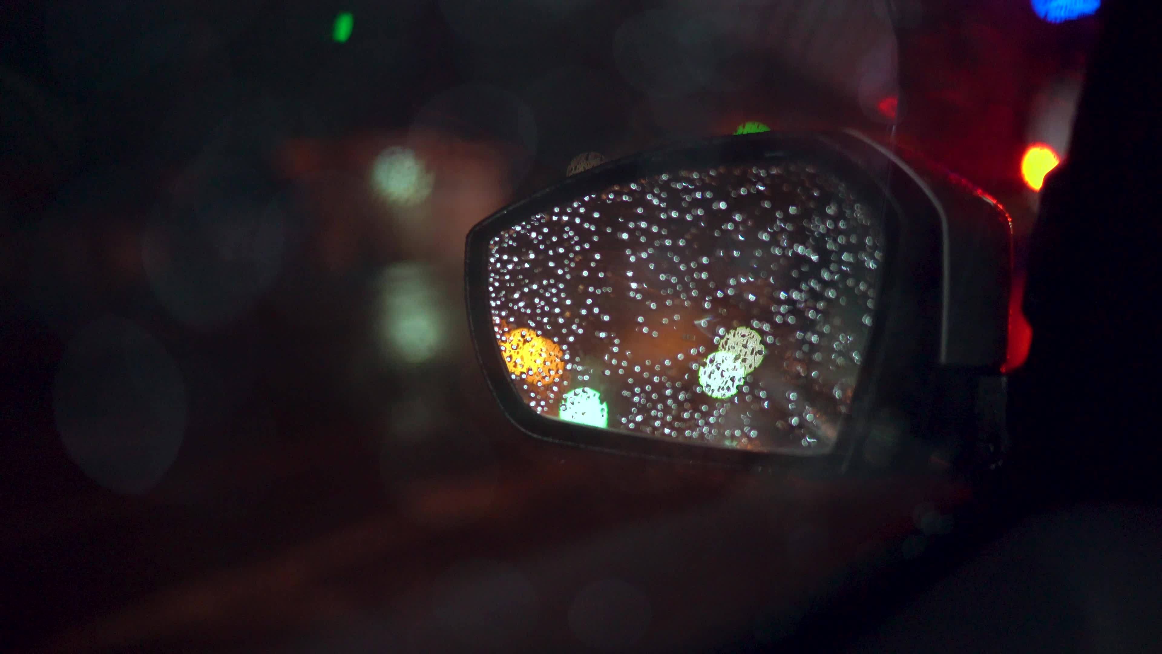 Close up rain drops on car window glass with blurred night city car