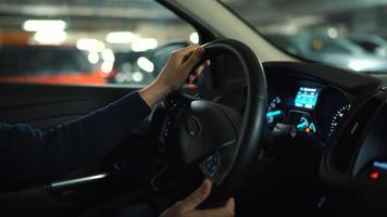 hombre conducción coche mediante un estacionamiento lote y es mirando para un sitio a parque o conducción lejos video