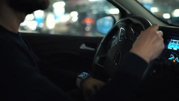 hombre conducción coche mediante un estacionamiento lote y es mirando para un sitio a parque o conducción lejos video