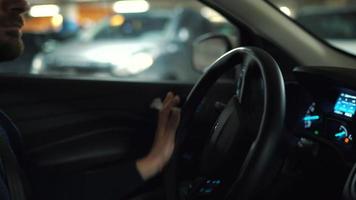 hombre conducción coche mediante un estacionamiento lote y es mirando para un sitio a parque o conducción lejos video