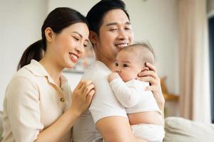 Smiling mother and father holding newborn son at home photo