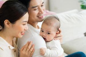 Smiling mother and father holding newborn son at home photo