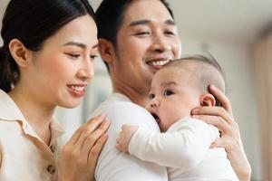 Smiling mother and father holding newborn son at home photo