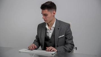 Jeune homme d'affaire dans costume en utilisant ordinateur clavier à travail video