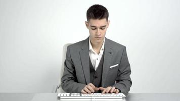 Jeune homme d'affaire dans costume en utilisant ordinateur clavier à travail video