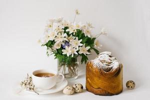 Easter sweet bread, cake and eggs with white apple flowers and primroses, a cup of tea. Festive breakfast concept with copy space. photo