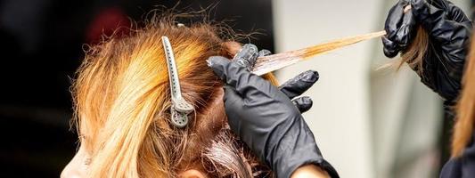 Hairdresser applying dye to strand of hair photo