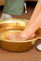 Female feet in a golden bowl with water in spa salon. Spa treatment. photo