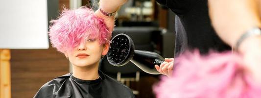 Hairdresser drying pink hair of client photo