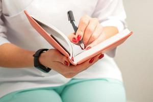 Close up of female doctor therapist writes notes in a medical notepad sitting in medical office. photo