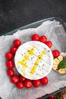 baked soft cheese Brie or Camembert tomato, garlic and herbs meal food snack on the table copy space food background rustic top view photo