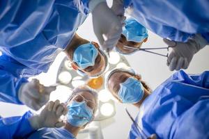 Surgeons standing above of the patient before surgery. Multi-ethnic healthcare workers performing surgery on patient at operation theater. photo