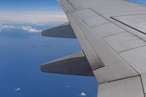 wing of aircraft flying above sea and islands photo