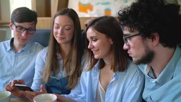 Young friends sit in a cafe, drink coffee and have fun communicating. Slow motion video