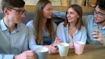 jong vrienden zitten in een cafe, drinken koffie en hebben pret communiceren. langzaam beweging video