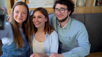 jong vrienden zitten in een cafe, drinken koffie en hebben pret communiceren. langzaam beweging video