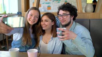 jong vrienden zitten in een cafe, drinken koffie en hebben pret communiceren. langzaam beweging video