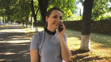 Woman talking to the phone while walking in the park video