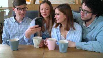 Young friends sit in a cafe, drink coffee and have fun communicating. Slow motion video