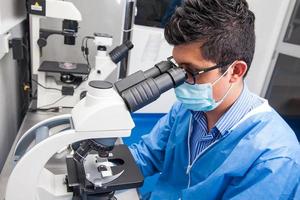 Young male scientist looking at slides under the microscope photo