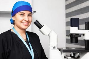 Beautiful young female scientist in the laboratory next to an  inverted microscope photo