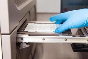 Scientist loading samples to a RT-PCR thermal cycler at the laboratory. Real-time polymerase chain reaction technique. RT-PCR technique photo