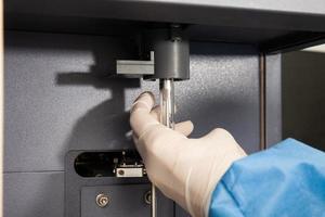 Scientist loading a test tube containing a patient sample on the  flow cytometer for analysis. Flow cytometer photo