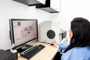 Young female scientist scanning microscope slides with tissue samples for pathology studies. Cancer diagnosis concept. Medical technology concept. photo