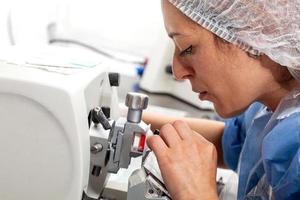 Young female scientist works on a rotary microtome to obtain sections from a paraffin-embedded specimen. photo