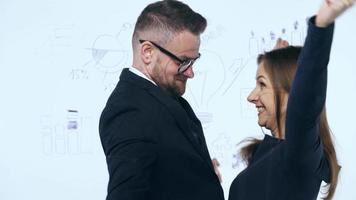 Man and woman shake hands and discuss the business strategy for success in a modern glass office video